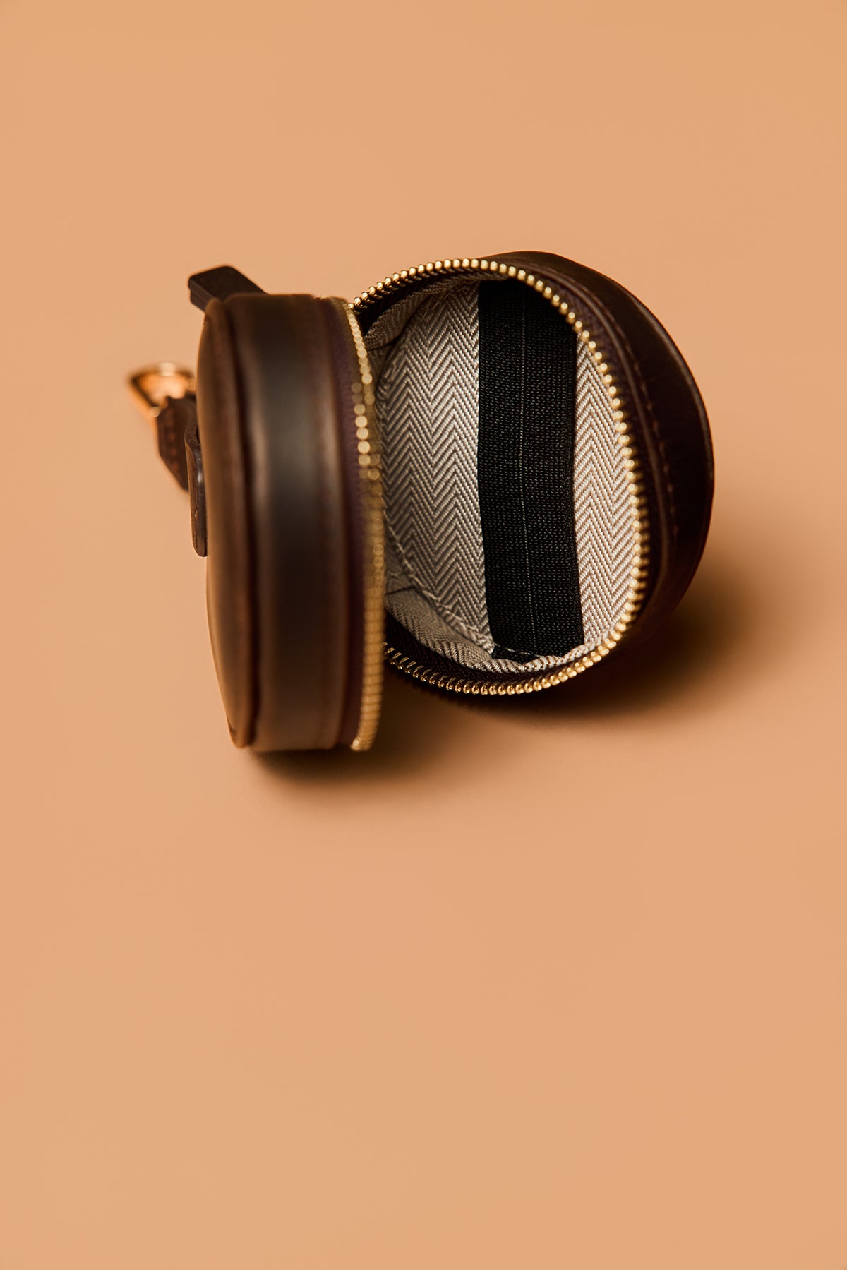 Brown leather case with a black and gray striped interior on a beige background