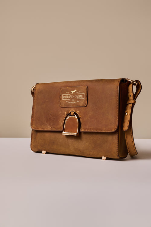 Brown leather bag with a visible brand label on a neutral background