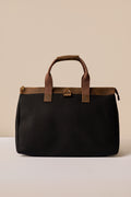 Black bag with brown leather accents on a beige background