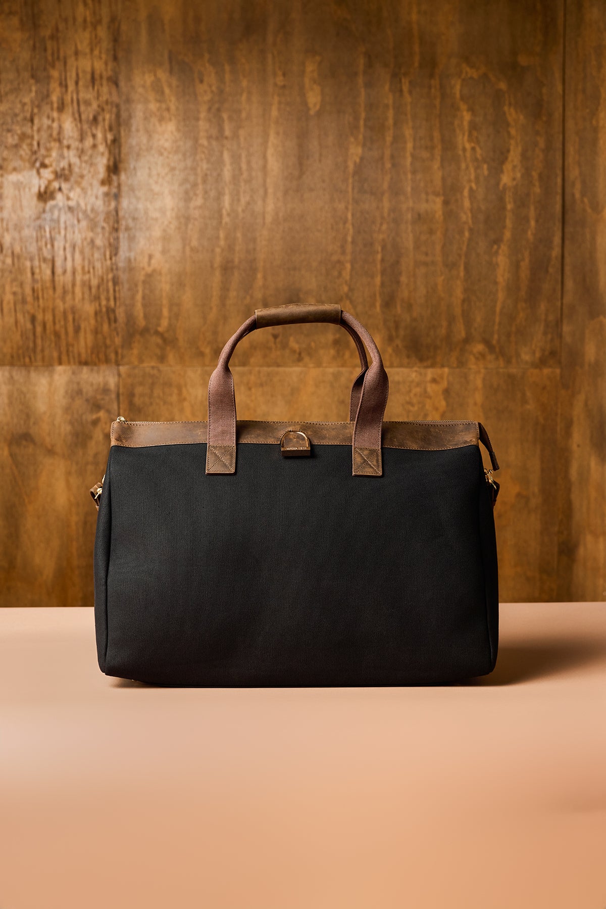 Black bag with brown handles on a wooden background