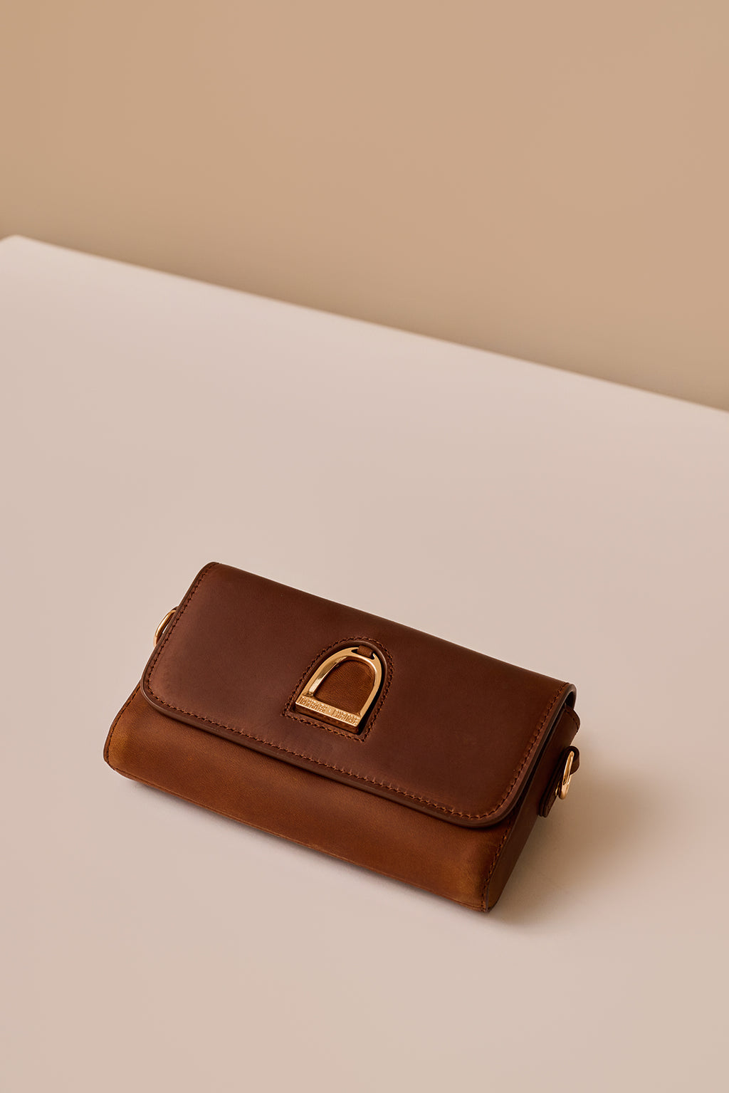 Brown leather wallet with gold buckle on a beige background