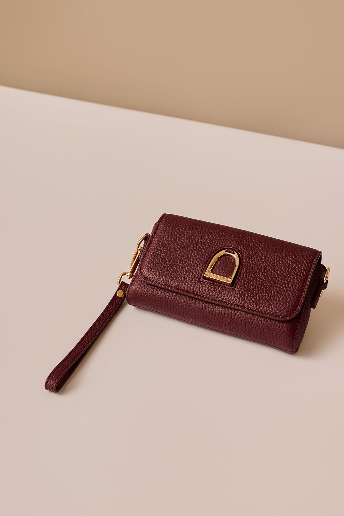 Brown leather wallet with a strap on a beige background