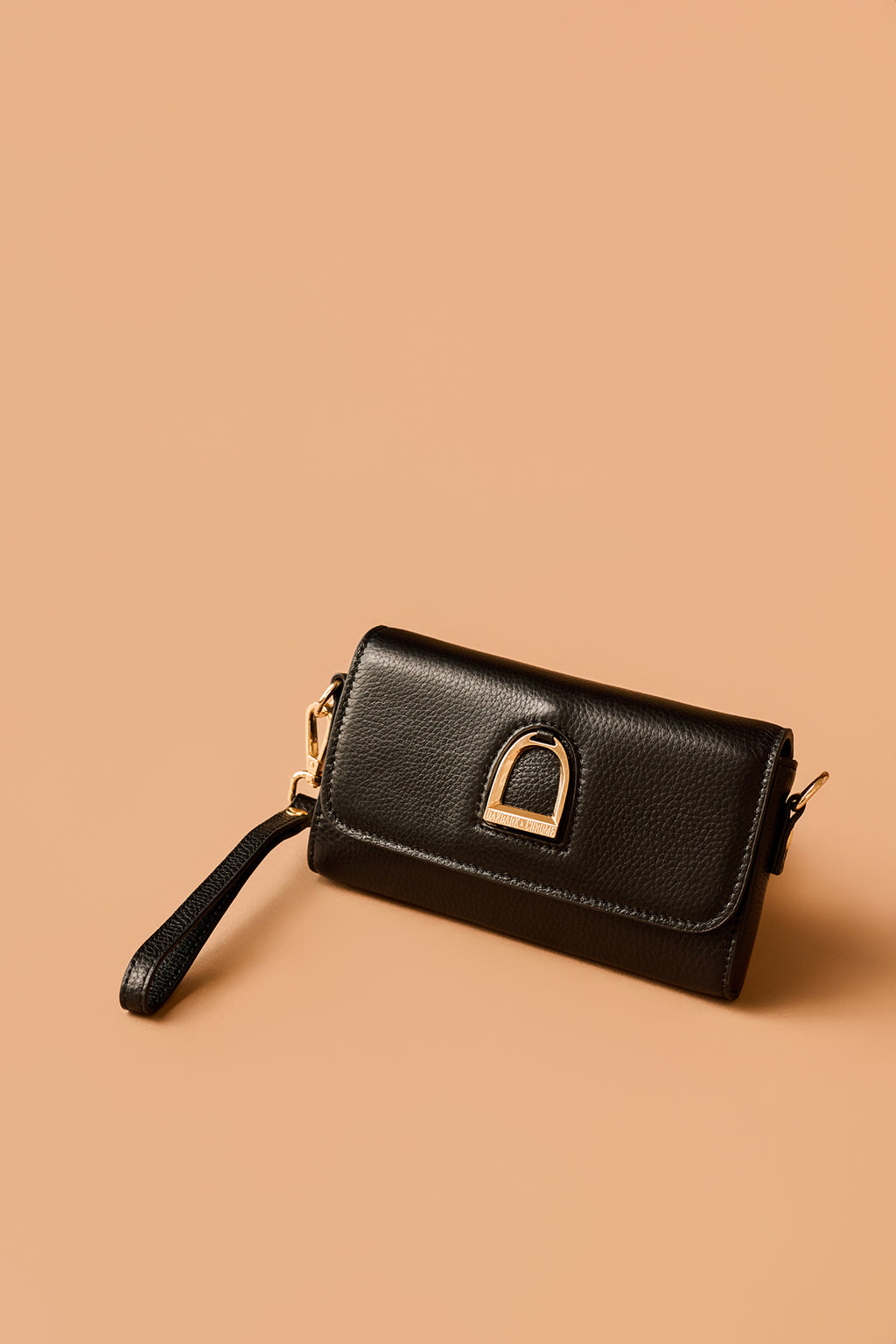 Black wallet with gold clasp on a beige background