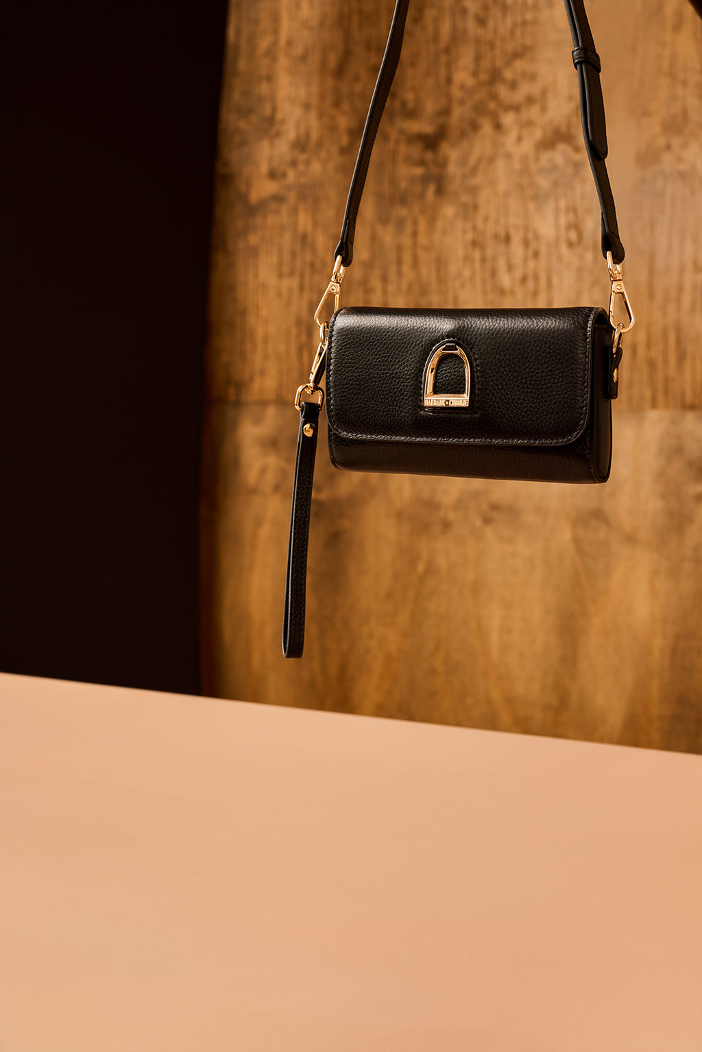 Black handbag with gold accents on a wooden surface