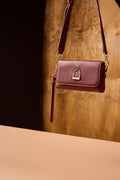 Purple handbag with a gold clasp on a wooden surface