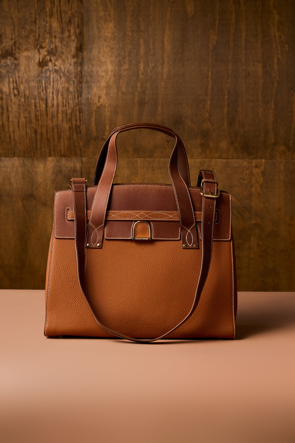 Brown leather handbag on a wooden surface with a wooden background