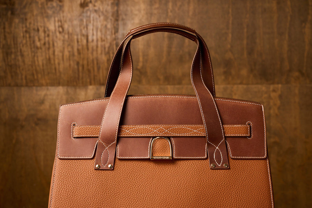 Brown leather handbag on a wooden background