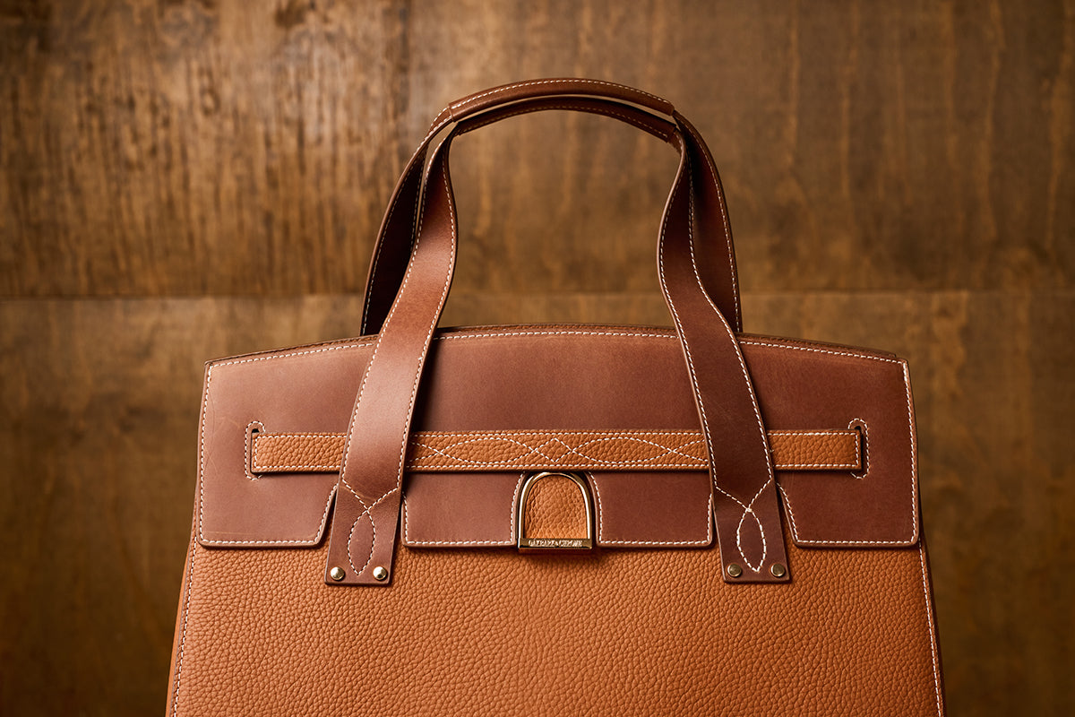 Brown leather handbag on a wooden background