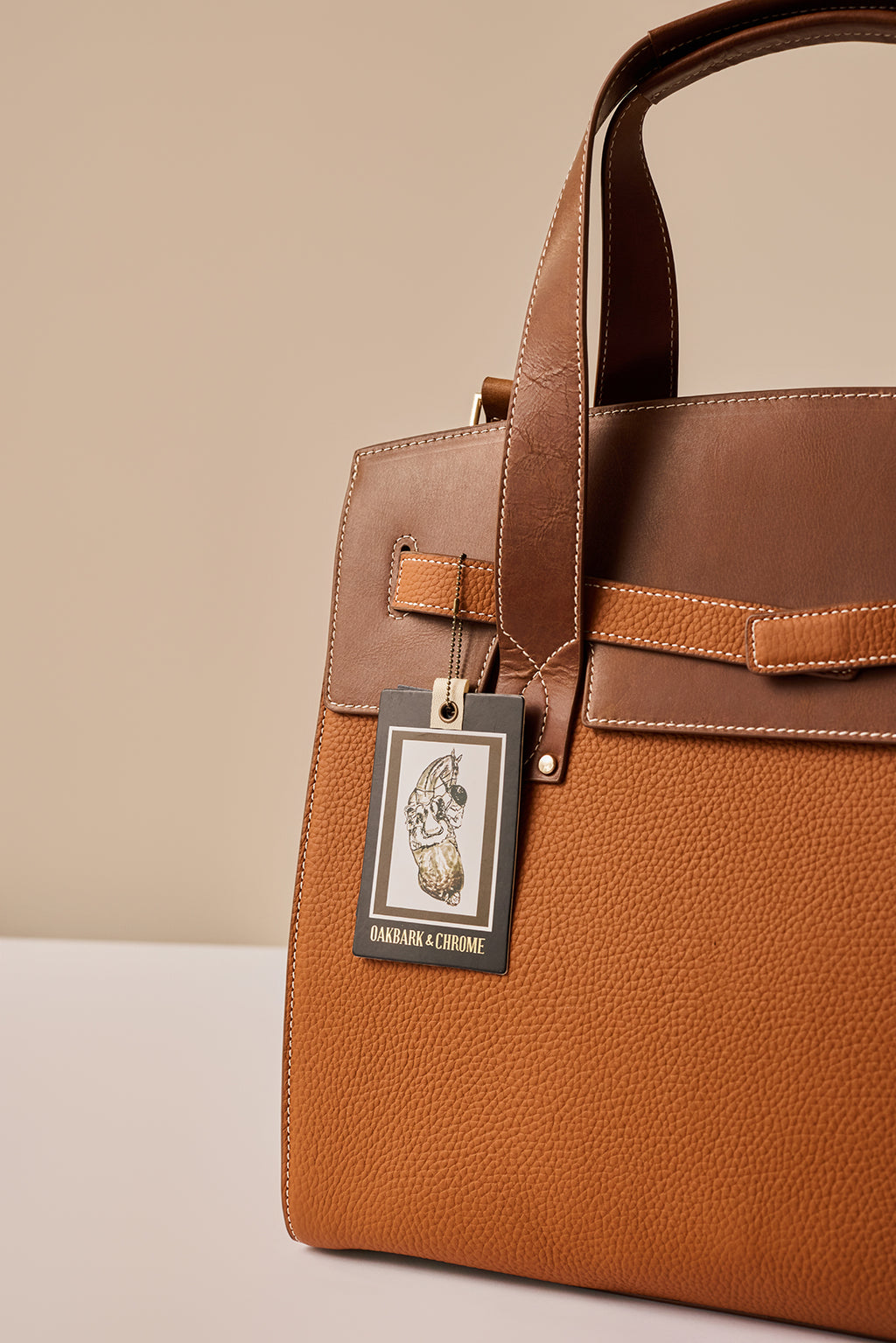 Brown leather handbag with a brand tag on a beige background