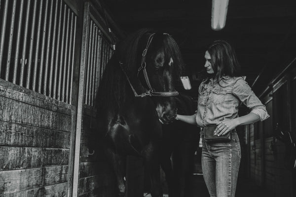 Woman standing next to a horse in a stable