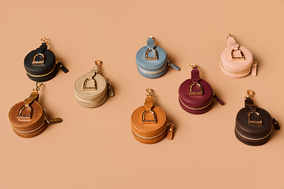 Set of small round leather bags in various colors on a beige background