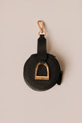 Black leather keychain with gold hardware on a beige background