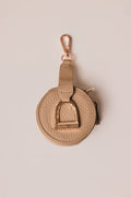Gold-colored keychain with a circular design on a beige background