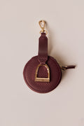 Wine leather keychain with gold horse stirrup on a beige background