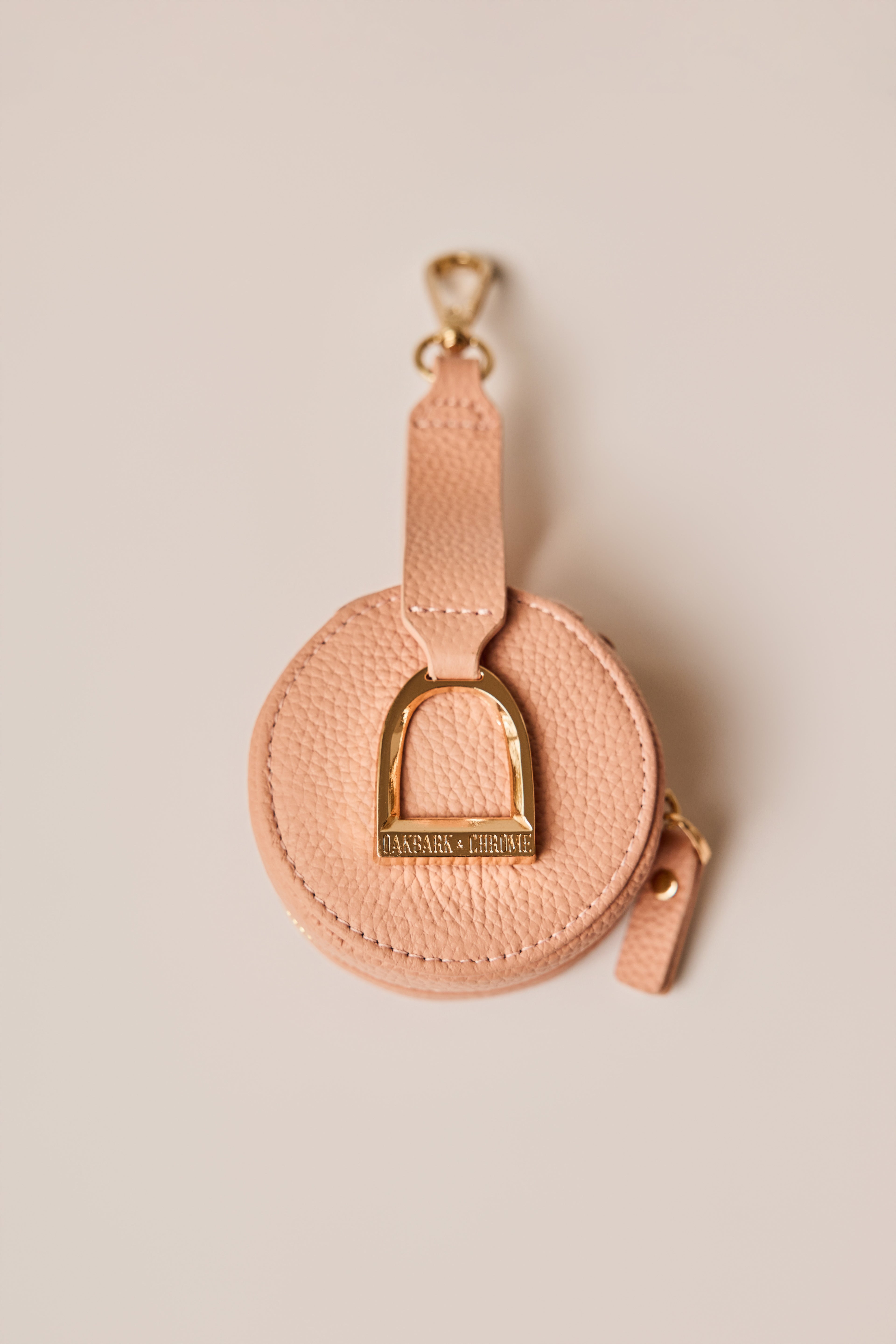 Pink leather keychain with gold hardware on a beige background