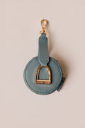 Teal round pouch with gold accents on a beige background