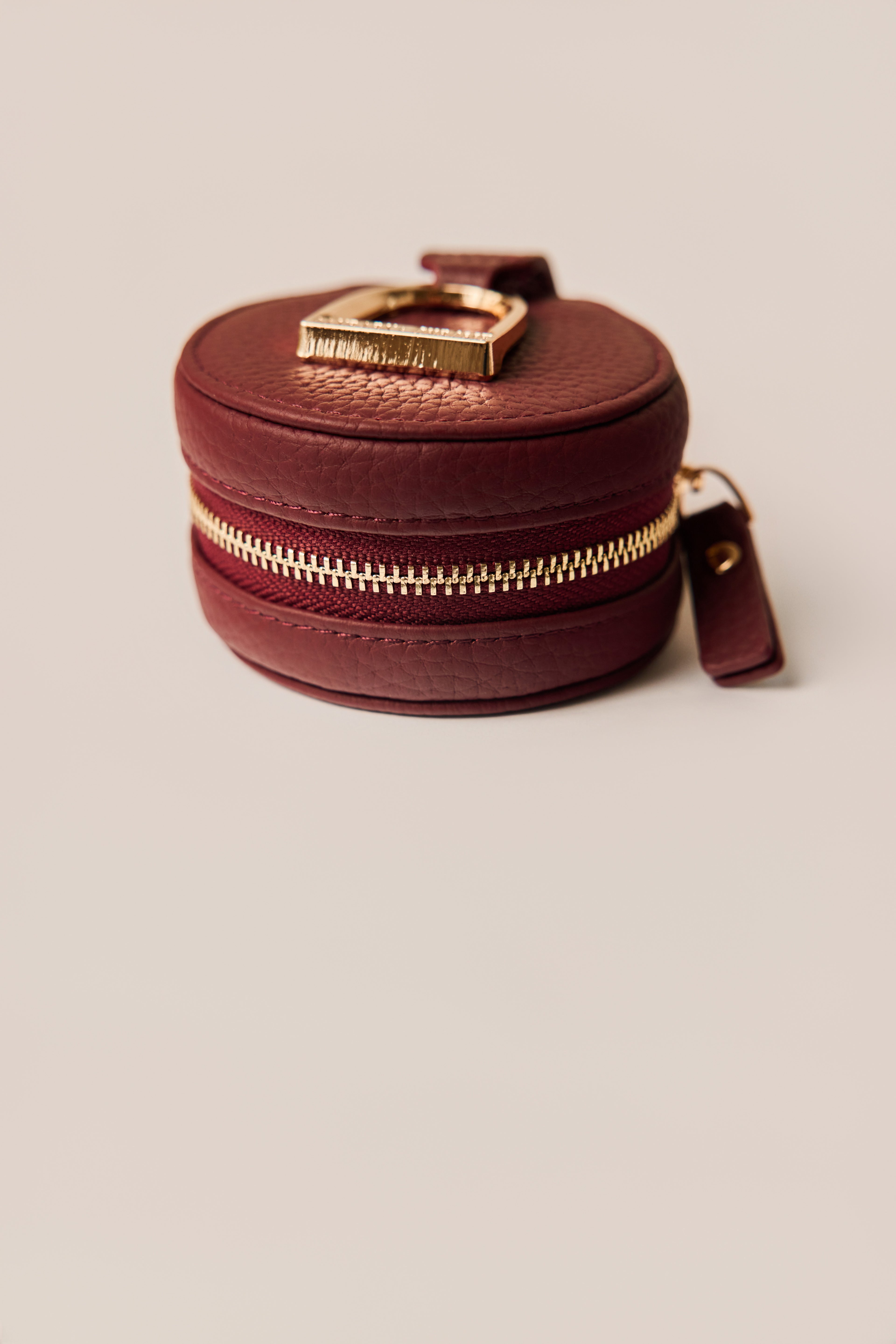 Wine leather keychain with gold horse stirrup on a beige background