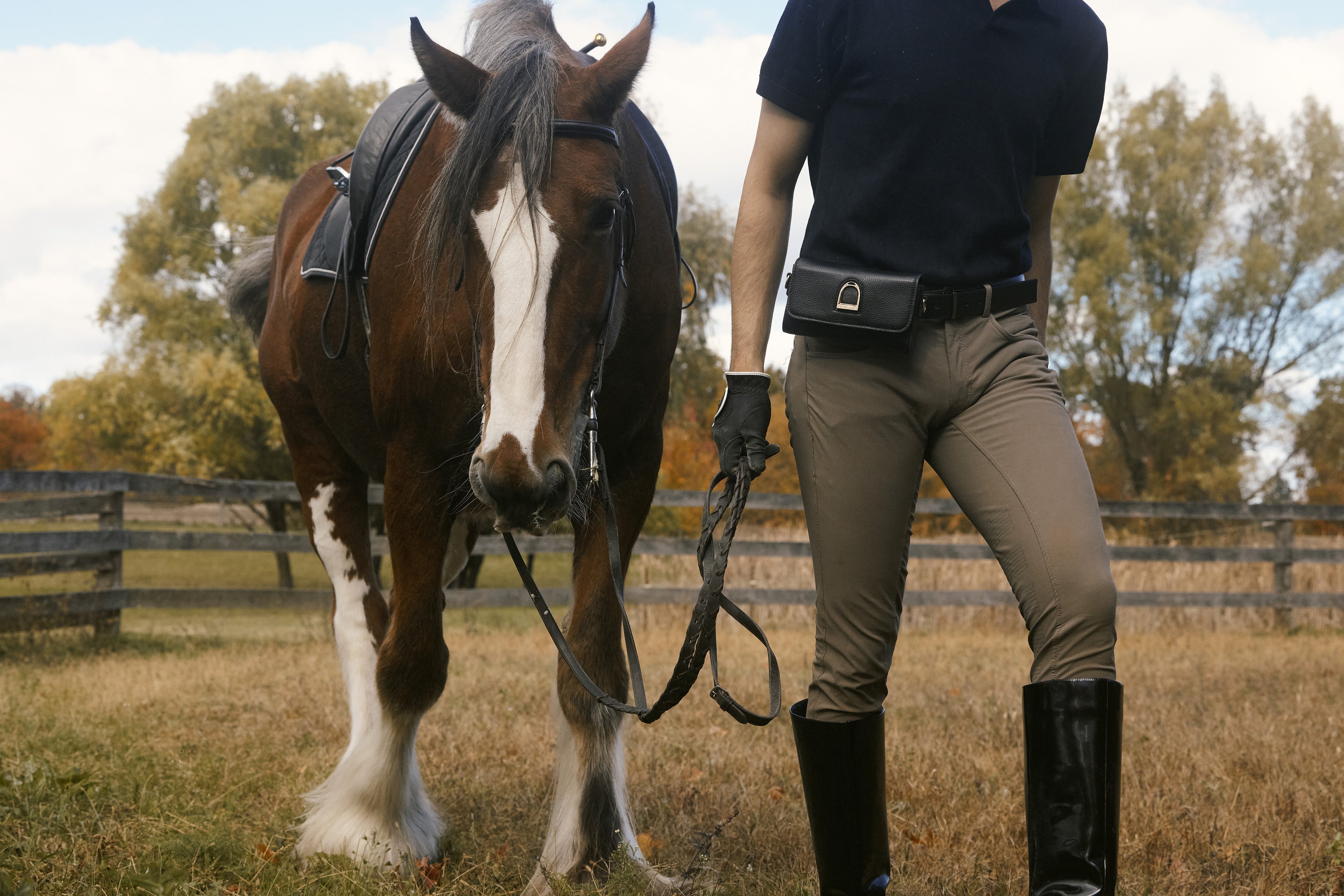Person in equestrian attire standing next to a horse in an outdoor setting