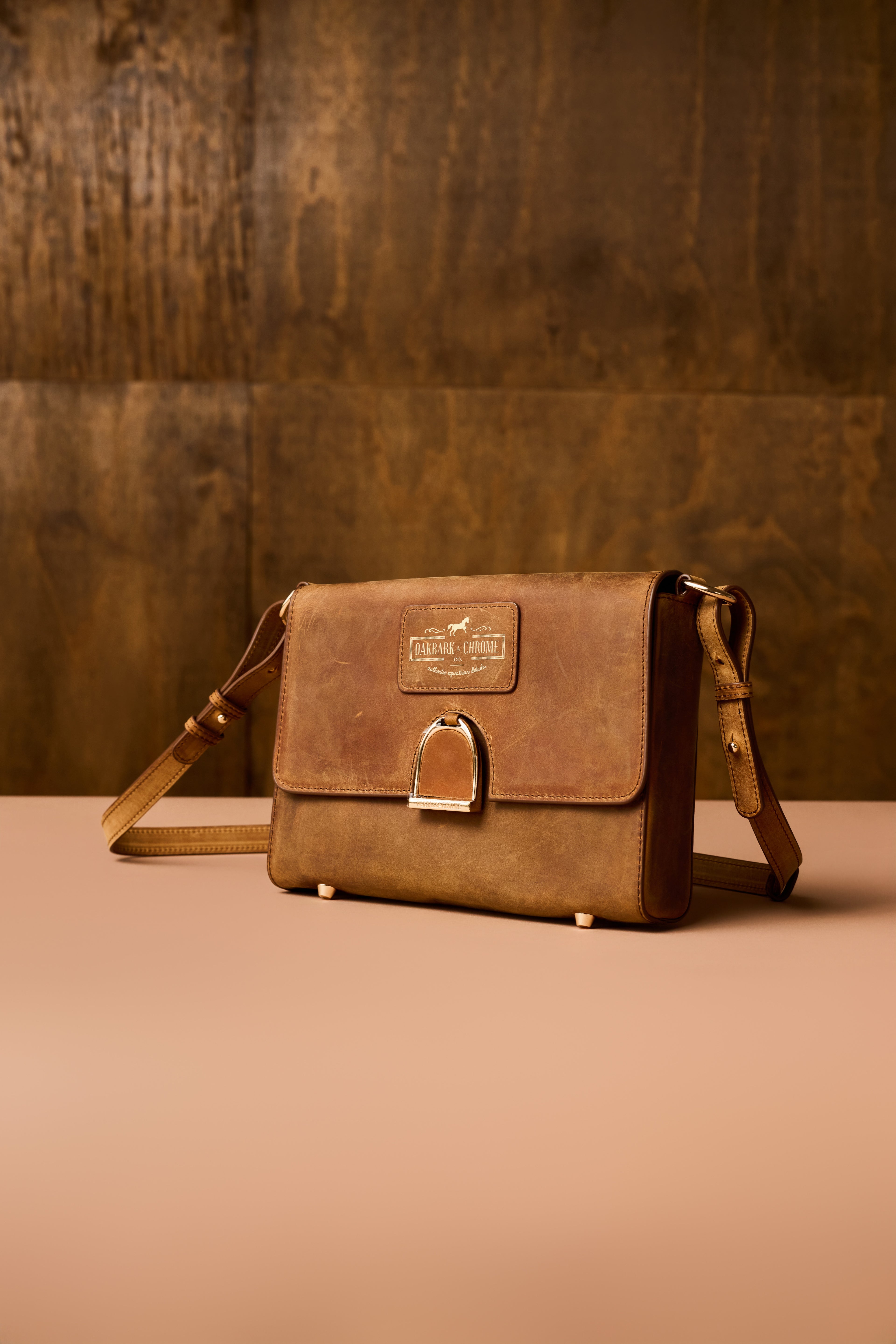 Brown leather bag with a strap on a brown background