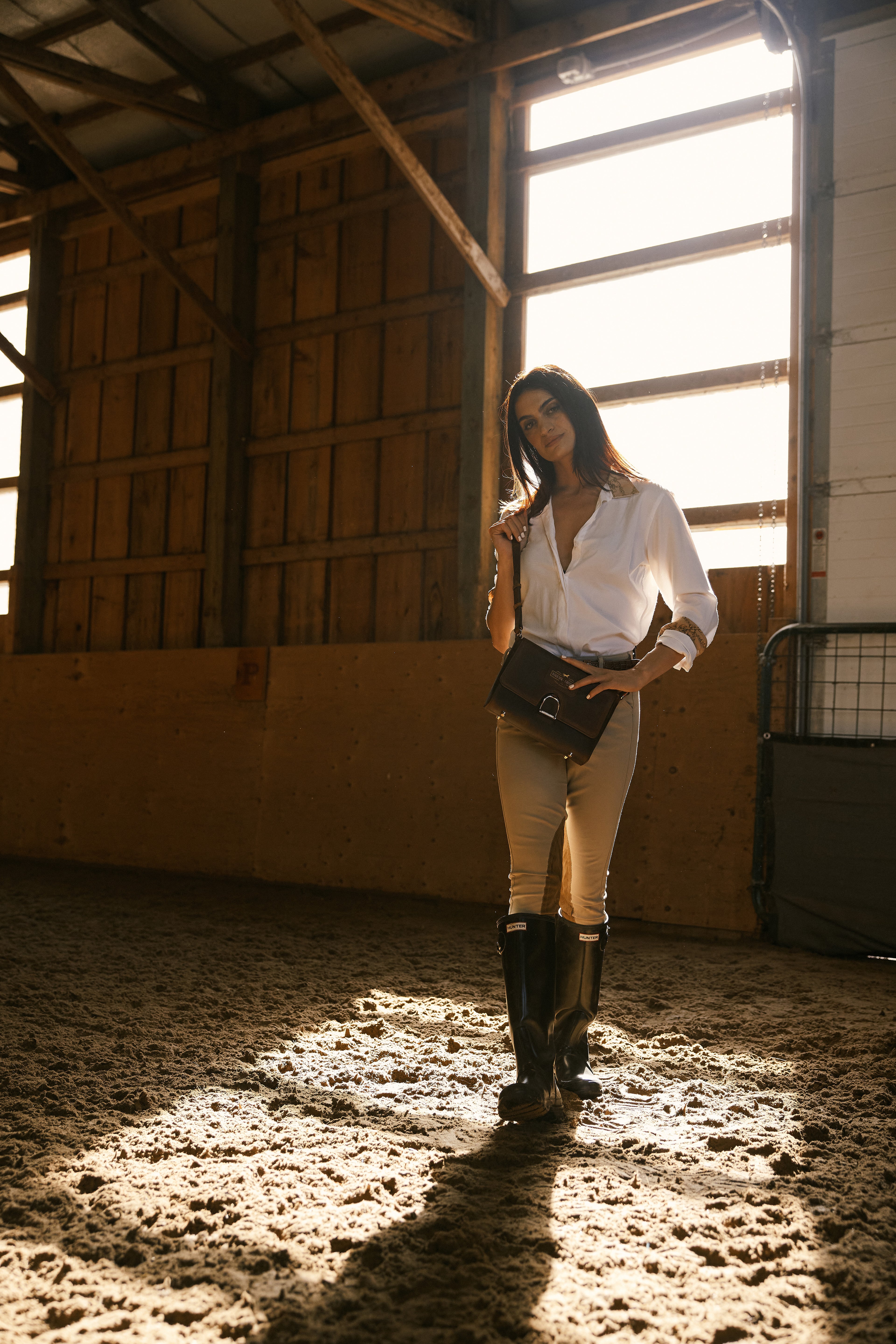 Woman in equestrian attire standing in a stable