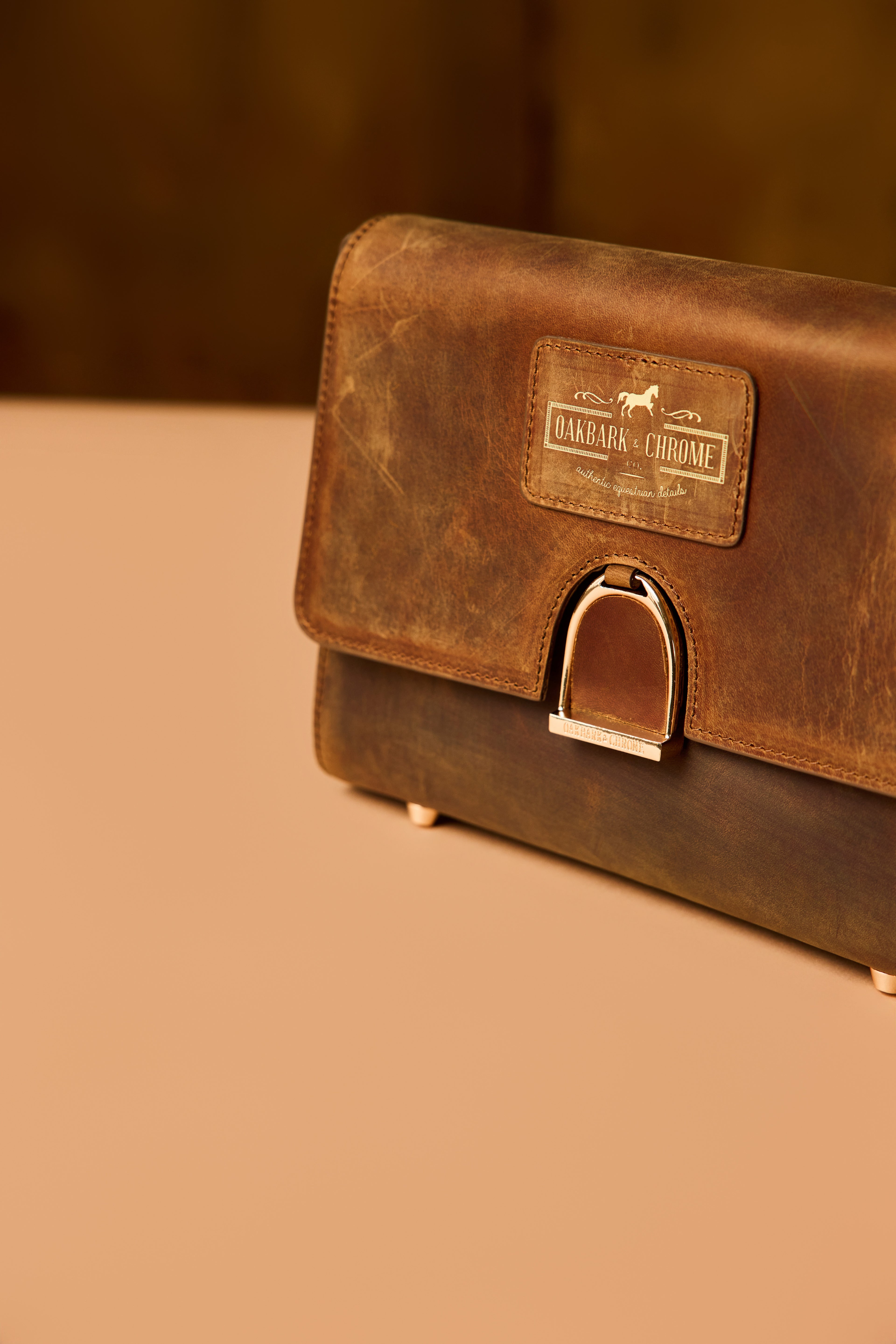 Rustic leather handbag off to the right, on a beige table in a warm brown room.