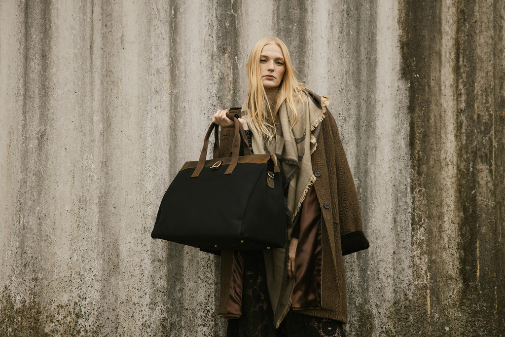 Woman holding a black bag against a textured wall